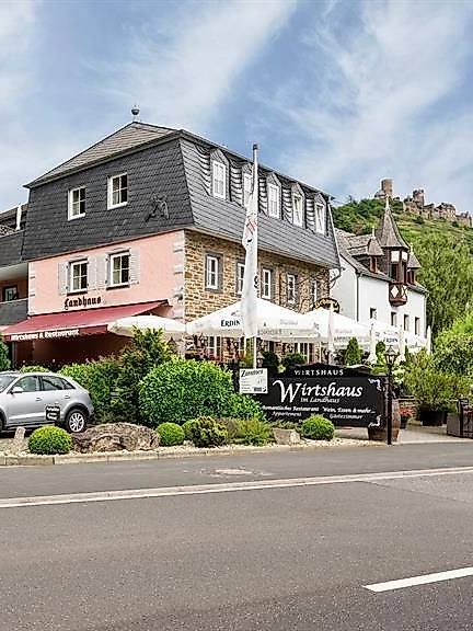 Ein charmantes Gasthaus mit einer modernen Fassade und umliegenden Weinbergen. Es befindet sich an einer ruhigen Straße mit Parkmöglichkeiten im Vordergrund.
