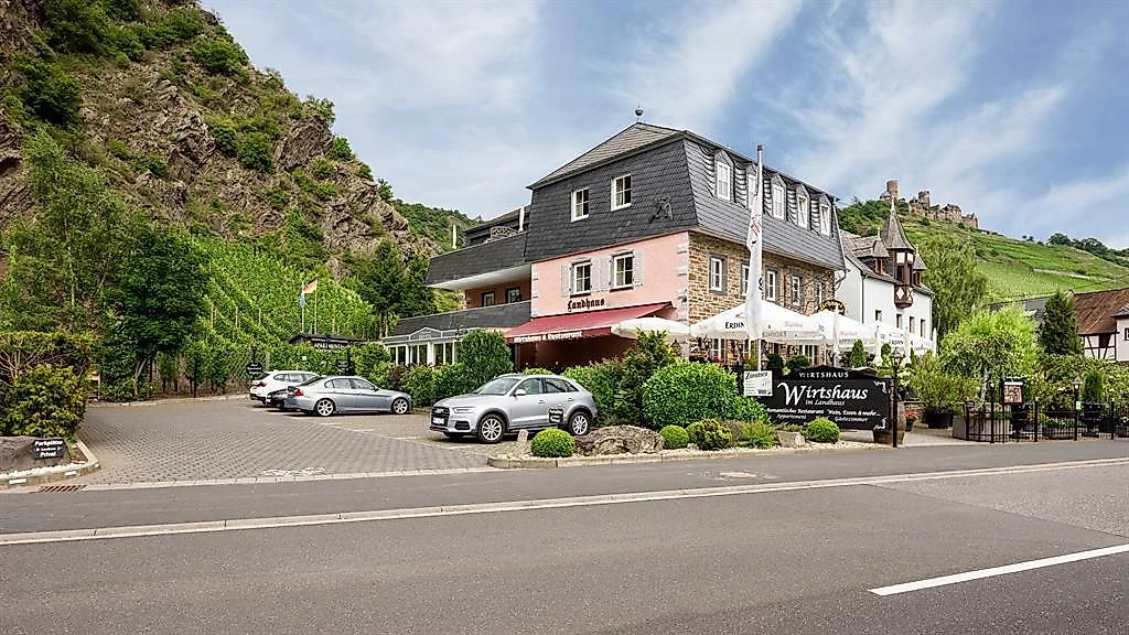 Ein charmantes Gasthaus mit einer modernen Fassade und umliegenden Weinbergen. Es befindet sich an einer ruhigen Straße mit Parkmöglichkeiten im Vordergrund.